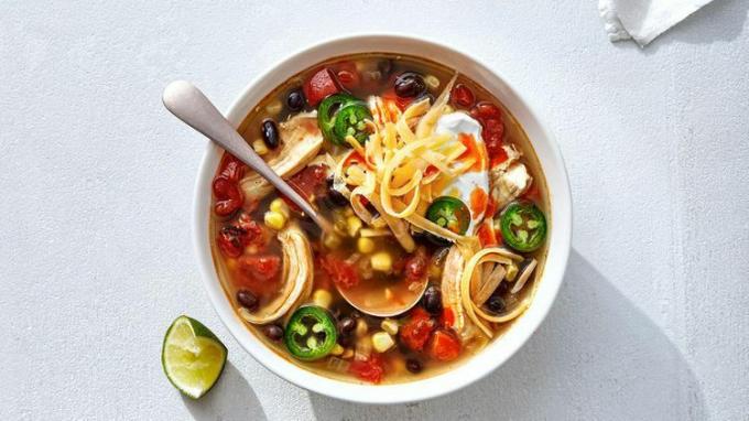 Bovenaanzicht van Slow Cooker Chicken Taco Soup geserveerd in een witte kom met een metalen lepel