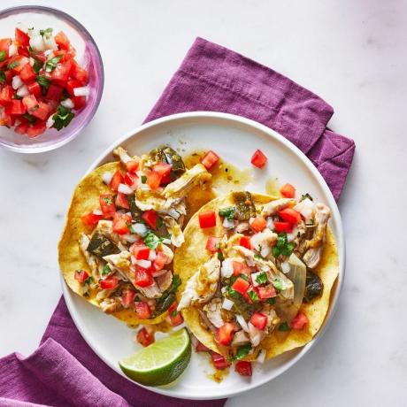 Slowcooker Chicken Tostadas met toppings op een witte plaat met een paars stoffen servet